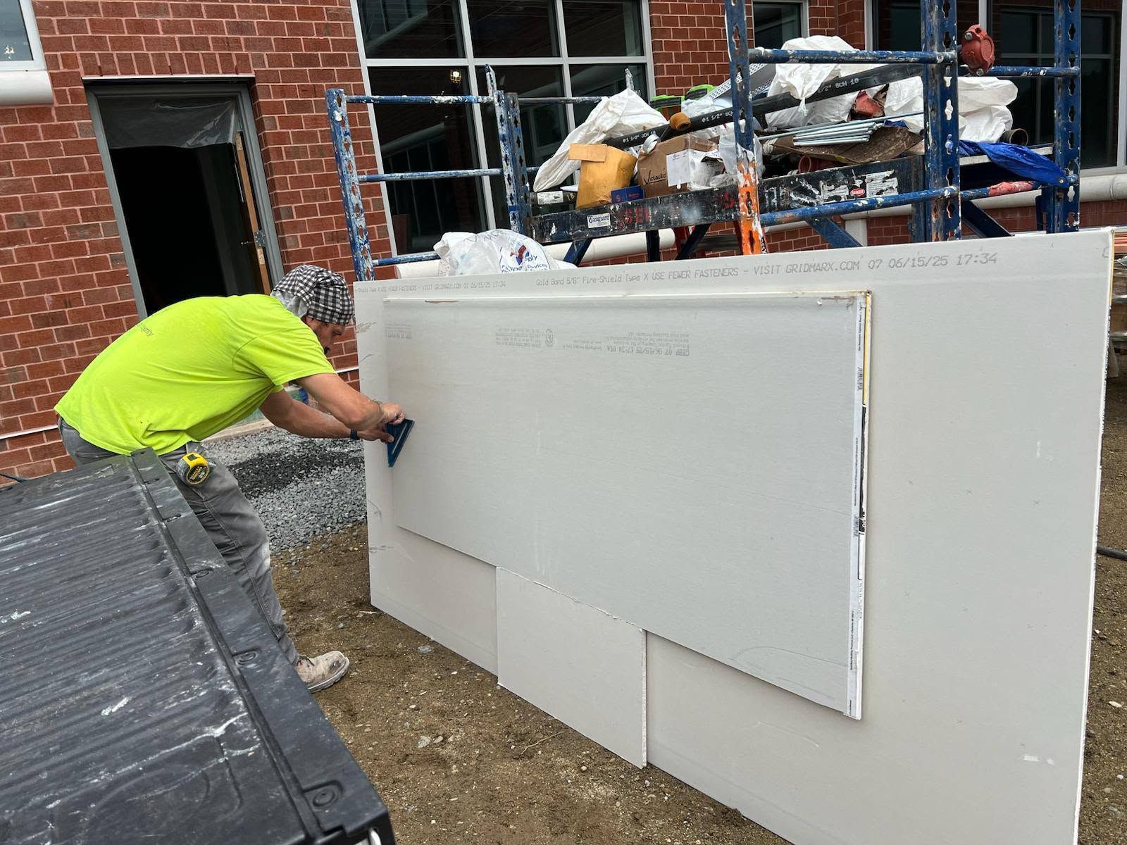E&I crew member measuring and cutting a drywall sheet outside the animal hospital in Portsmouth, NH